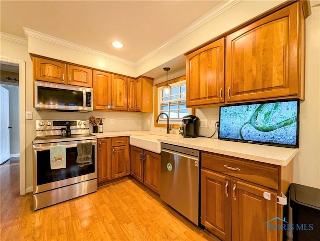 509 Oakwood Ave, Bryan, OH 43506 - kitchen with light countertops, light wood-type flooring, a sink, appliances with stainless steel finishes, and brown cabinetry