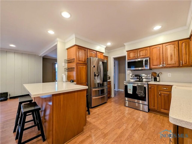 509 Oakwood Ave, Bryan, OH 43506 - kitchen with a breakfast bar, light wood-style floors, a peninsula, appliances with stainless steel finishes, and brown cabinetry