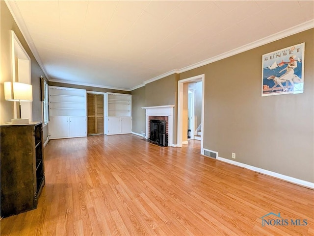 509 Oakwood Ave, Bryan, OH 43506 - unfurnished living room with light wood-type flooring, baseboards, visible vents, and a brick fireplace