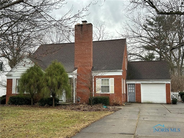 view of front of house with brick siding, concrete driveway, a front yard, a chimney, and an attached garage