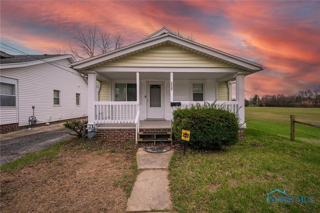 bungalow-style home featuring covered porch and a yard