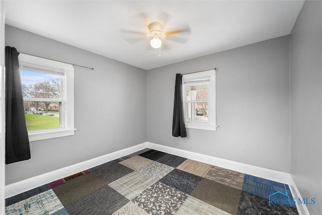 spare room featuring baseboards, a wealth of natural light, visible vents, and a ceiling fan