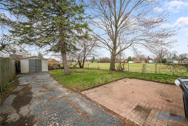 view of yard featuring a fenced backyard, a patio area, an outdoor structure, and a storage shed