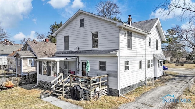 rear view of house with roof with shingles and a sunroom