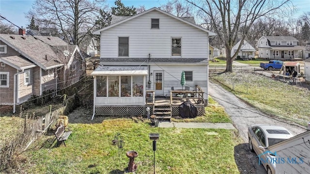 rear view of house with a yard and a sunroom