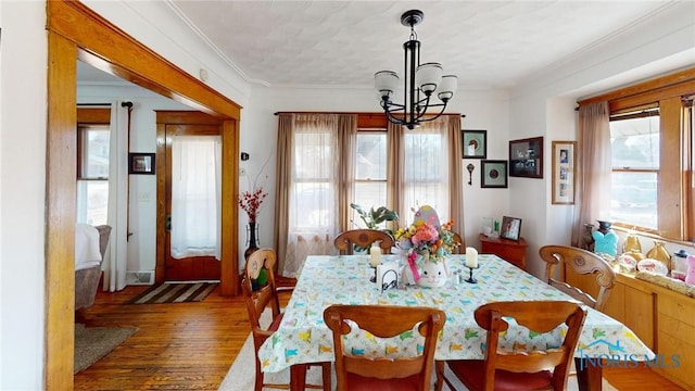 dining area featuring crown molding, wood finished floors, and a chandelier