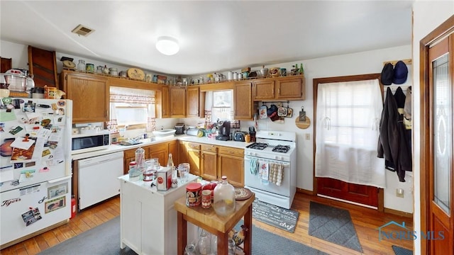 kitchen featuring visible vents, white appliances, light wood-type flooring, and light countertops