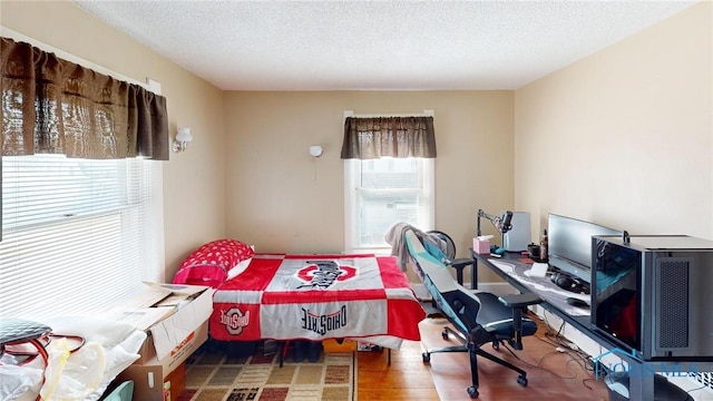 bedroom with a textured ceiling and wood finished floors