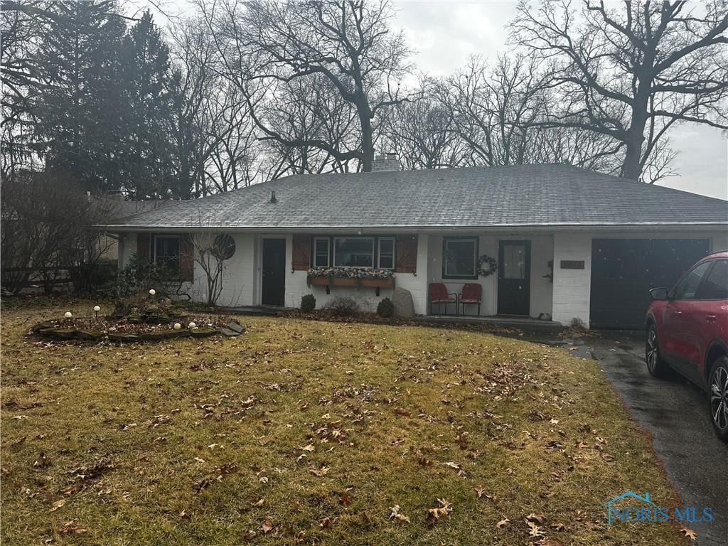 single story home with a front yard, driveway, a porch, an attached garage, and a shingled roof