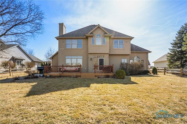 back of property featuring a yard, a deck, a chimney, and a fenced backyard