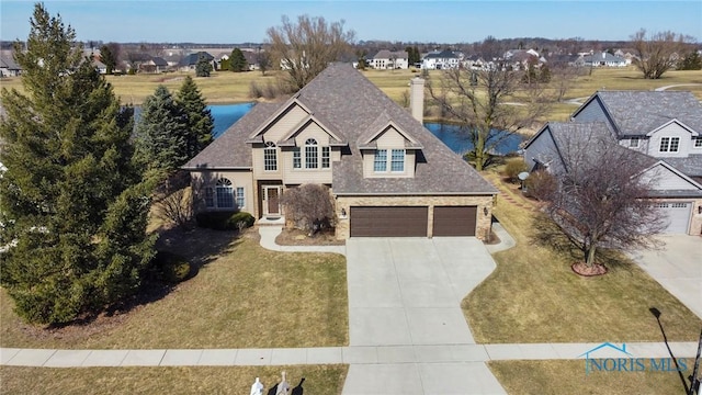 traditional-style house featuring a garage, roof with shingles, concrete driveway, and a front lawn