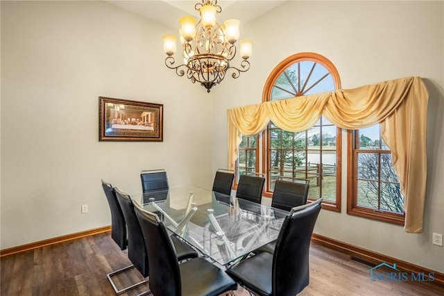 dining area with a notable chandelier, visible vents, baseboards, and wood finished floors