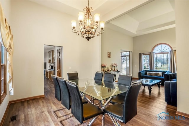 dining area with visible vents, baseboards, wood finished floors, and a chandelier