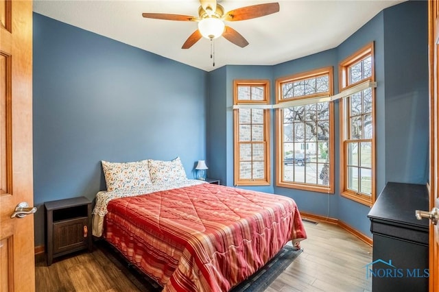 bedroom with visible vents, a ceiling fan, baseboards, and wood finished floors