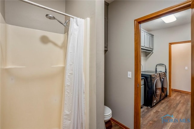 bathroom featuring baseboards, washer and clothes dryer, toilet, a shower with shower curtain, and wood finished floors