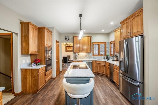 kitchen with dark wood finished floors, a kitchen island, stainless steel appliances, and a sink