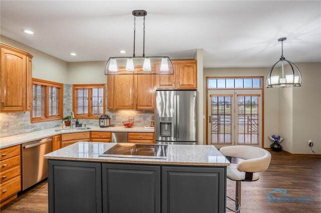 kitchen with a sink, backsplash, dark wood finished floors, a center island, and stainless steel appliances