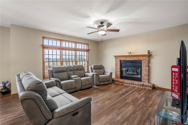 living area with a brick fireplace, wood finished floors, baseboards, and ceiling fan