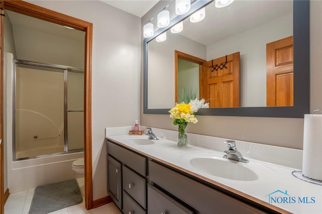 bathroom featuring a sink, toilet, shower / bath combination with glass door, and double vanity