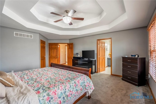 bedroom featuring a raised ceiling, baseboards, visible vents, and carpet floors