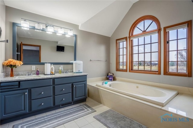 bathroom featuring double vanity, lofted ceiling, a bath, and a sink