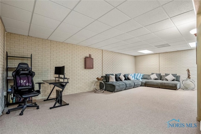 exercise room featuring a drop ceiling, carpet floors, and brick wall