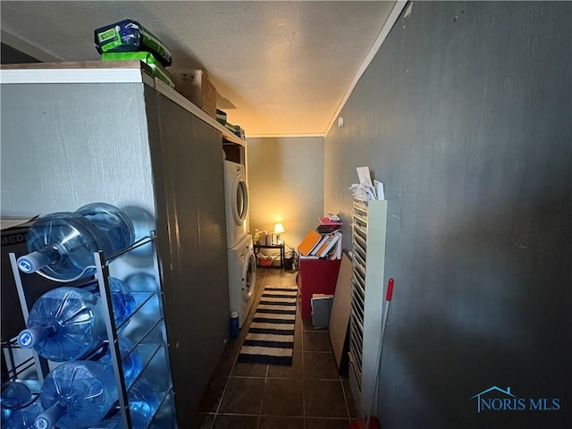 hallway featuring tile patterned flooring, a textured ceiling, crown molding, and stacked washer and dryer