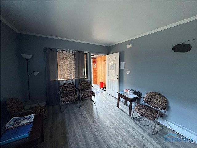 living area featuring baseboards, wood finished floors, and ornamental molding