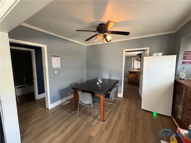 dining area featuring visible vents, crown molding, baseboards, wood finished floors, and a ceiling fan