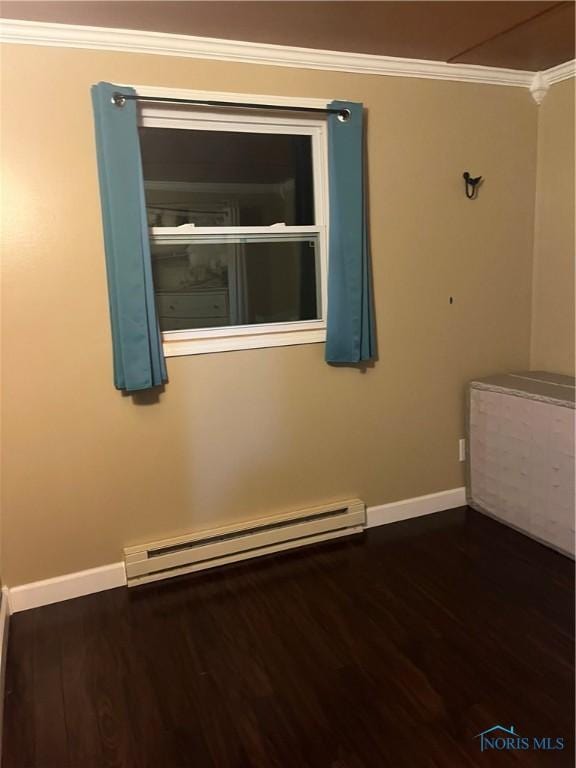 spare room with crown molding, a baseboard heating unit, baseboards, and wood finished floors