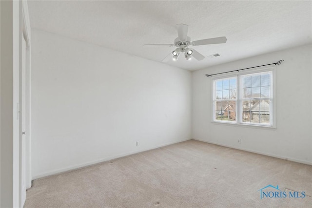 spare room featuring carpet flooring, visible vents, and a ceiling fan