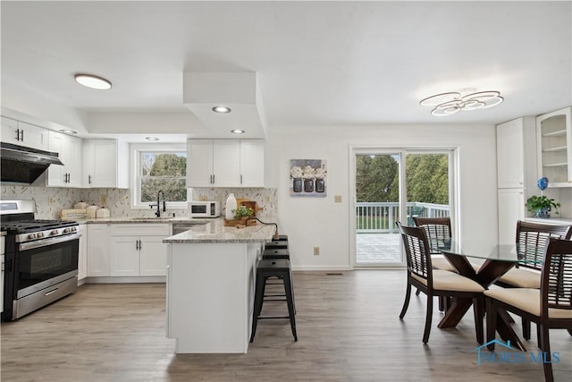 1004 Waterville Monclova Rd, Waterville, OH 43566 - kitchen featuring a sink, decorative backsplash, under cabinet range hood, appliances with stainless steel finishes, and a kitchen breakfast bar