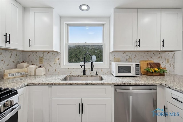 1004 Waterville Monclova Rd, Waterville, OH 43566 - kitchen with light stone countertops, a sink, decorative backsplash, stainless steel appliances, and white cabinetry