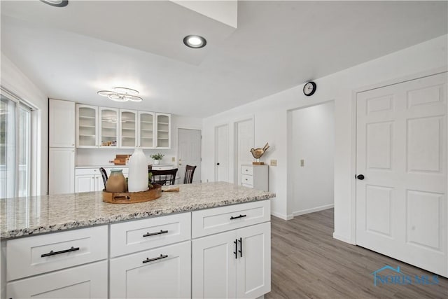1004 Waterville Monclova Rd, Waterville, OH 43566 - kitchen featuring baseboards, white cabinets, light wood finished floors, glass insert cabinets, and light stone countertops