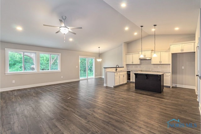 unfurnished living room featuring vaulted ceiling, dark wood-type flooring, a ceiling fan, and a sink