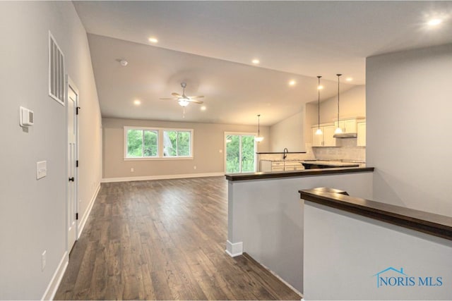 hallway featuring visible vents, dark wood-type flooring, baseboards, vaulted ceiling, and recessed lighting