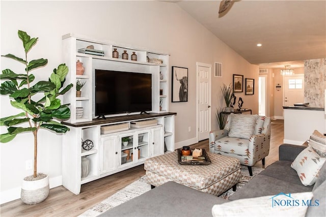 living area featuring visible vents, baseboards, wood finished floors, and vaulted ceiling