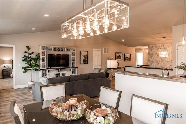 dining area featuring visible vents, wood finished floors, recessed lighting, an inviting chandelier, and vaulted ceiling