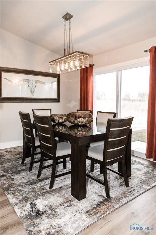 dining room featuring vaulted ceiling, baseboards, and wood finished floors
