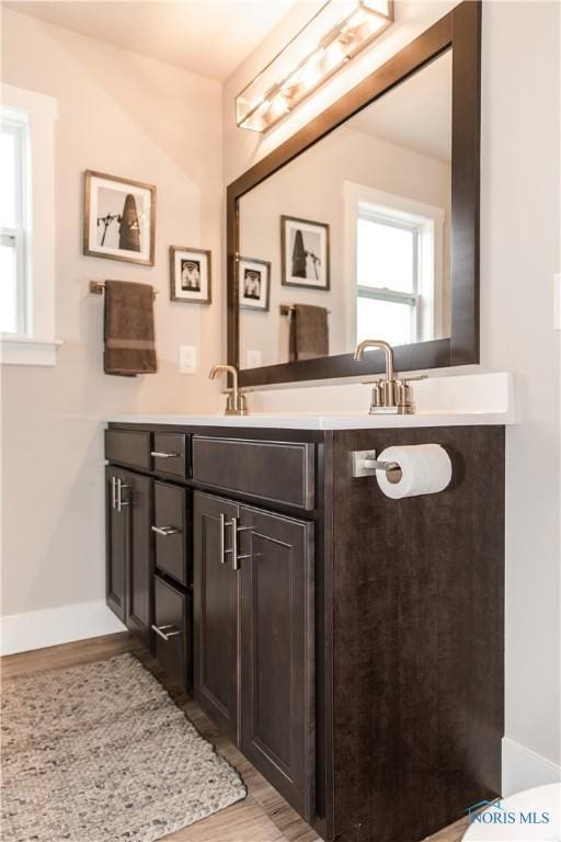bathroom featuring baseboards, wood finished floors, and vanity