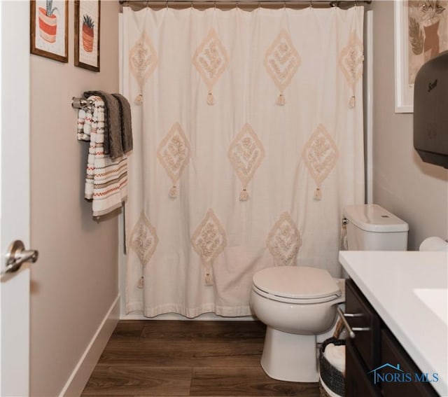 bathroom with toilet, wood finished floors, a shower with shower curtain, baseboards, and vanity