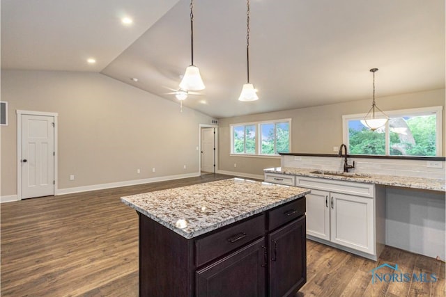 kitchen featuring a sink, pendant lighting, lofted ceiling, white cabinets, and dark wood-style flooring