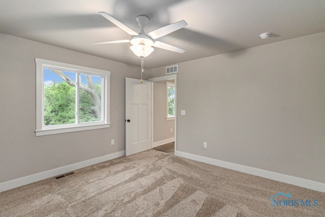 carpeted spare room with visible vents, a ceiling fan, and baseboards