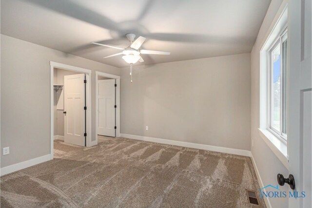 unfurnished bedroom with a ceiling fan, baseboards, visible vents, carpet floors, and a spacious closet