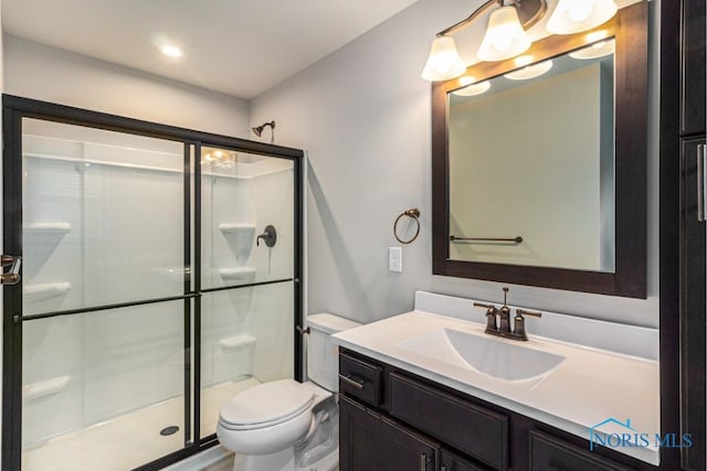 bathroom featuring vanity, a shower stall, and toilet