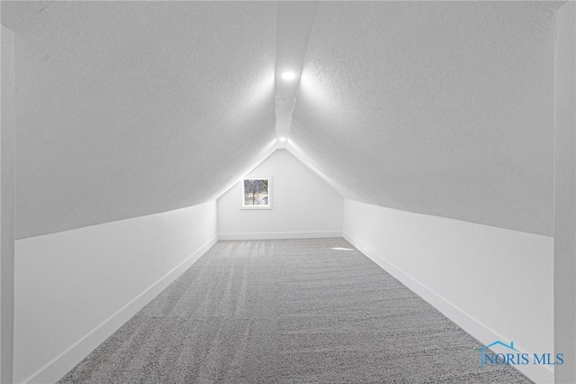 bonus room featuring baseboards, a textured ceiling, lofted ceiling, and carpet floors
