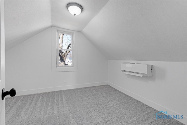 additional living space featuring baseboards, lofted ceiling, carpet, and an AC wall unit
