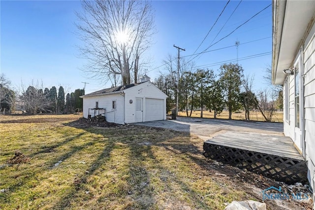 view of yard featuring a deck, an outdoor structure, a garage, and driveway