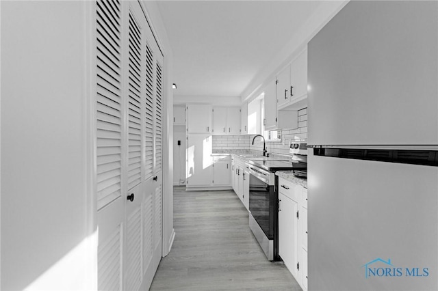 kitchen with light countertops, decorative backsplash, light wood-style flooring, appliances with stainless steel finishes, and white cabinets