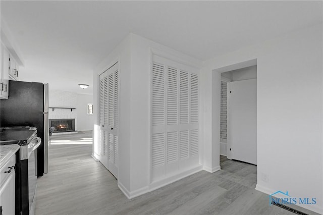 corridor featuring light wood-style flooring and baseboards